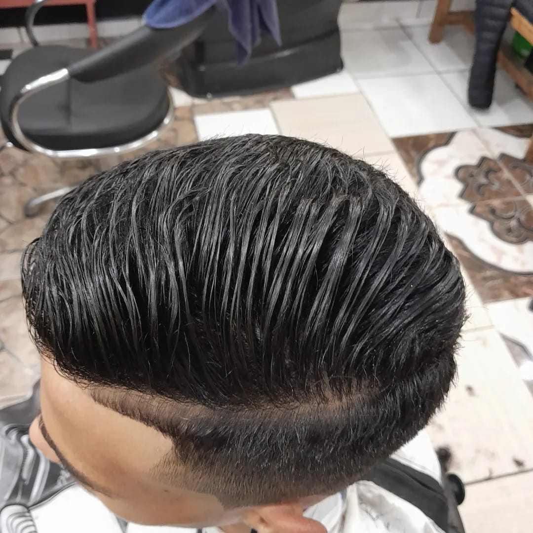 corte com topo penteado para trás e degradê nas laterais, feito na cadeira de barbearia